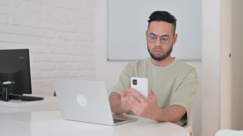Hispanischer Mann, der mehrere Geräte für die Arbeit verwendet