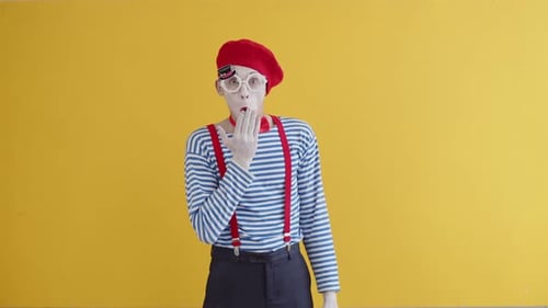 Der junge Pantomime ist sehr überrascht und bedeckt seinen Mund mit seiner Handfläche
