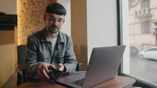 Young Adult Working on Laptop Answers Phone