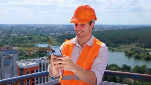 Construction Worker Using Phone on City Rooftop