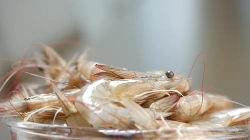 There are shrimps on a table and in a bowl, both in a restaurant