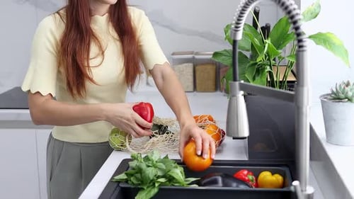 Una joven saca verduras y frutas orgánicas de una bolsa reutilizable en la cocina moderna