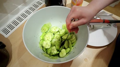 In a white bowl, stir cucumber salad with a spoon