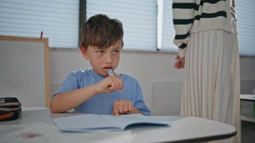 Small Kid Working Diligently in Notebook in Elementary School Class Closeup