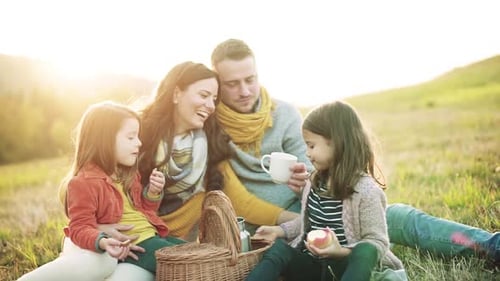 Happy family enjoying picnic in nature at sunset