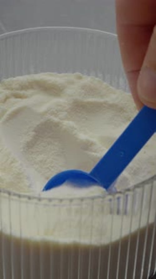 Scooping Powdered Milk Formula with a Blue Scoop