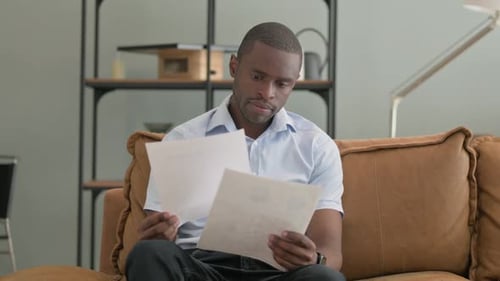 Man Reading Important Documents on Couch Indoors