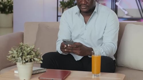 Man Relaxing on Couch Using Smartphone