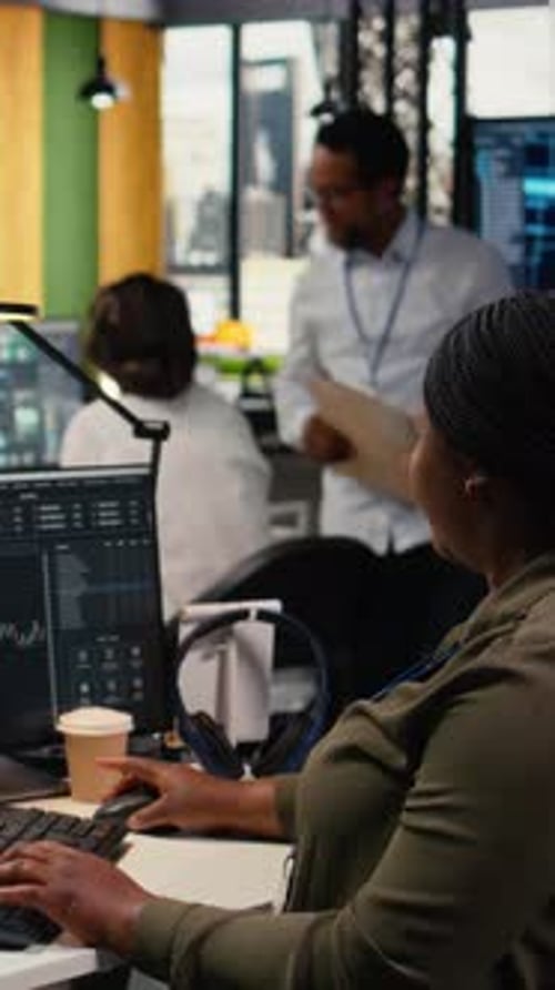 Smiling Woman Working at Computer in Busy Office