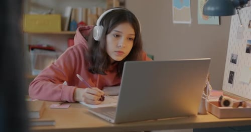 Student Studies With Laptop and Takes Notes