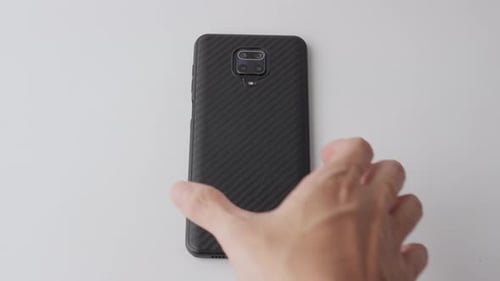 Hand Placing Mobile Phone on White Surface