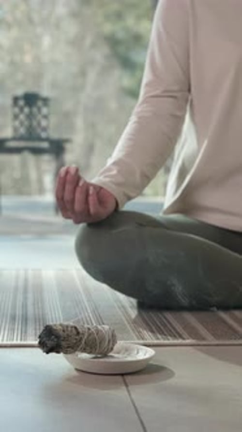 Person Meditating With Smoking Incense At Home