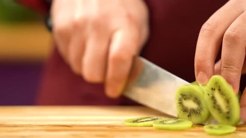 Hands Slice Fresh Kiwi Fruit on Cutting Board