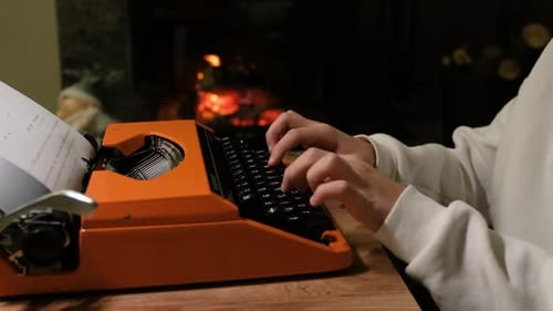 Typing on Orange Typewriter by Warm Fireplace