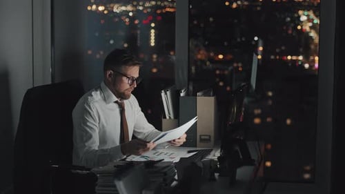Exhausted Male Executive Working at Night Alone in Office