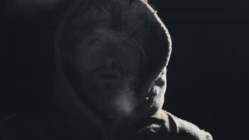Un homme au visage gelé. Un jeune homme adulte à la barbe glacée et au chapeau respire à l'extérieur à une température inférieure à zéro