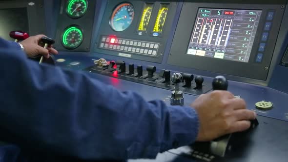 Train operator in blue uniform managing controls in locomotive cabin ...
