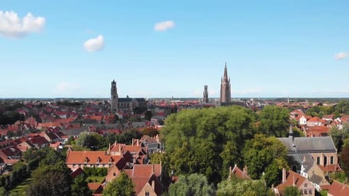 Famous landmarks rise high above the red rooftops in Bruges, Belgium, aerial HD
