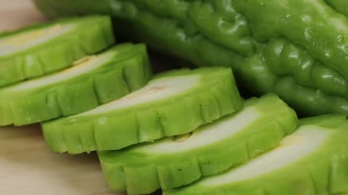 Une gourde amère, un légume souvent utilisé comme ingrédient en cuisine, est posée sur une table en bois.