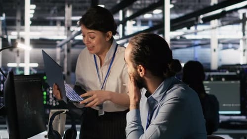 Coworkers Discussing Code in a Server Room