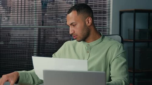 African American Young Businessman Working in Office Looking Through Paper Documents Analyzing Data