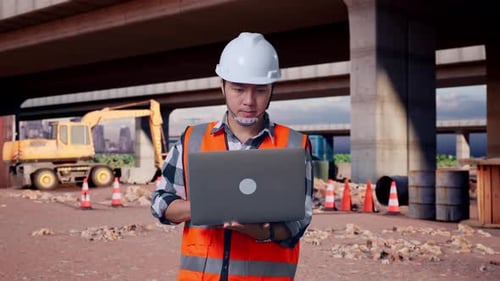 Asian Male Engineer Working On A Laptop At Building Site