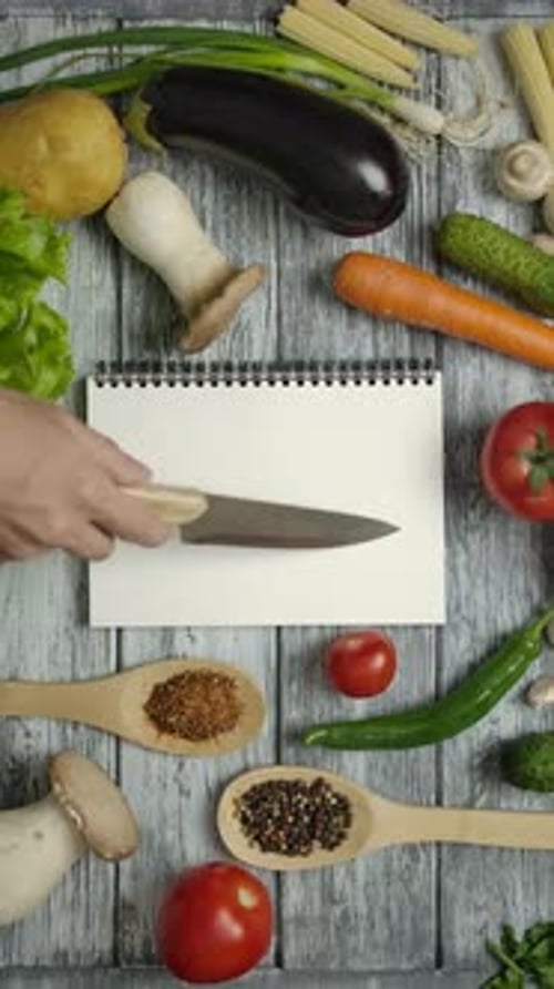 Vertikale oder gesichtslose Köchin mit Messer zum Lesen des Rezepts. Einfach das Rezept auf leeres Papier legen