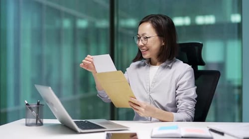 Woman at Desk Opens Envelope and Reads Letter