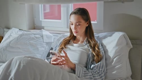 Woman Relaxing in Bed Using Mobile Phone