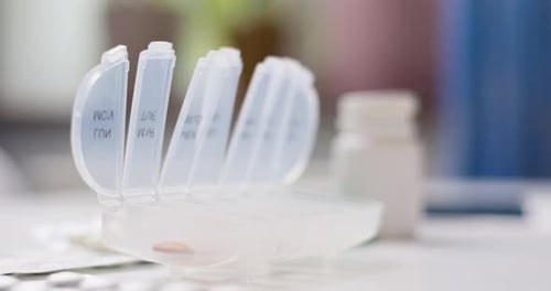 Male Hand Putting Pills Into Open Pill Organizer or Plastic Pillbox