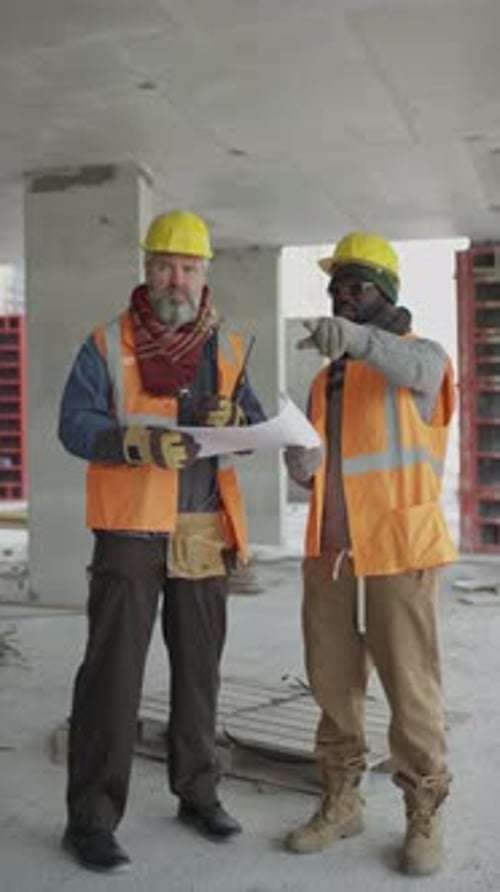 Construction Workers Discuss Plans at Building Site