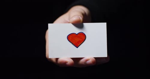 Close Up of Hand Holding Heart Drawing