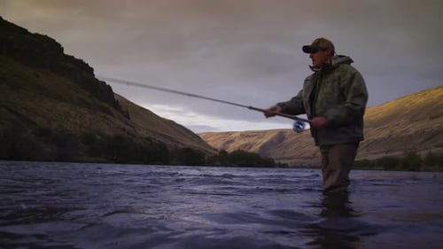 Man fly fishing for salmon in the deschutes river Oregon at sunrise