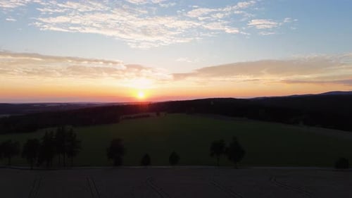 A beautiful golden view of the sunset from a drone in the mountains as the camera slowly descends to
