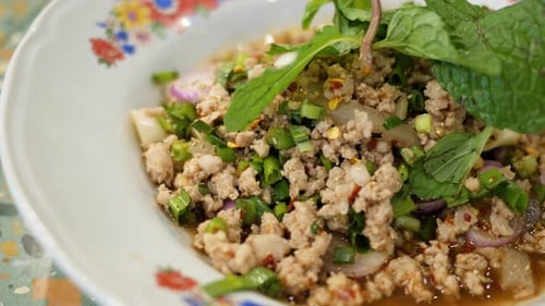 Close up of a plateful of a popular Isan Thai food called Larb, a mixture of minced chicken, mint, c