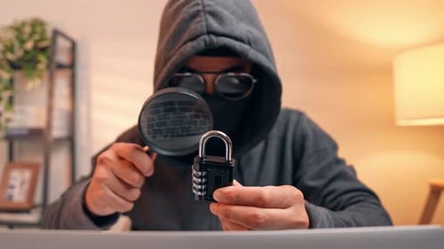 A hacker inspects a combination lock with a magnifying glass.