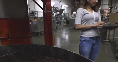 Woman Uses Laptop Near Roasting Coffee Beans