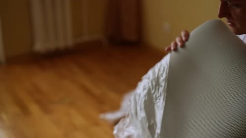 L'homme retire soigneusement le film protecteur d'une nouvelle pièce de chaise d'ordinateur avant l'assemblage pour l'entretenir