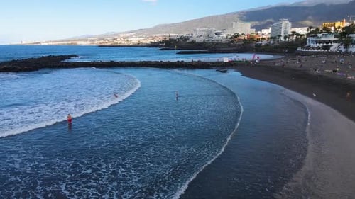 Luftaufnahme von Touristen, die den Strand und die Wellen auf der Insel Teneriffa mit Atlantik genießen