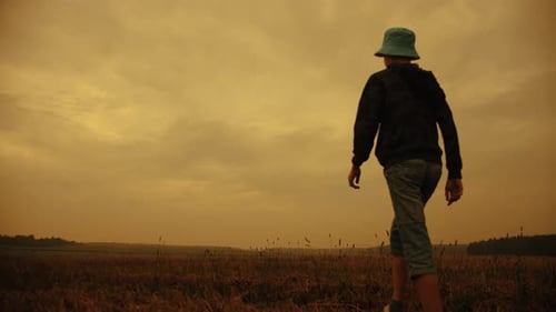 Child Standing with Arms Raised on Golden Horizon