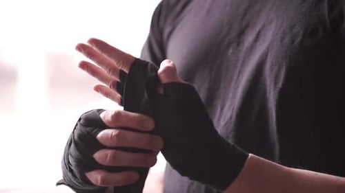 Male Boxer Wraps His Hands with a Bandage Before Training