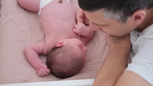 Father affectionately tending to infant in crib