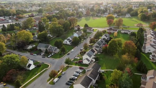 Small town in USA. Homes and rental apartment units with colorful trees. Rising aerial pull-back dro