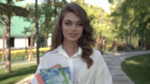 Smiling Young Woman Walking on Tree-Lined Path