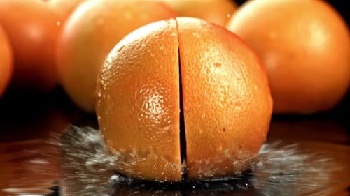 Juicy grapefruit halves splashing in water