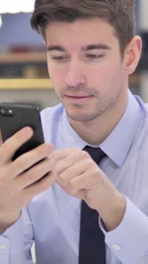 Young Man Using Smartphone in an Office