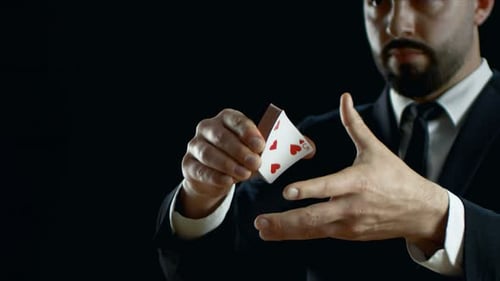 Close-up of a Professional Magician in a Black Suit Performing Card Trick. Throwing and Catching Ca