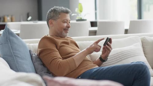 Man Relaxes on Couch with Smartphone Indoors