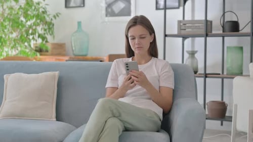 Woman Using Smartphone Device While Sitting on Sofa
