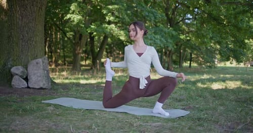 Young Beautiful Athletic Woman in Sportswear Doing Stretching and Warming Up in the Park Near a Tree